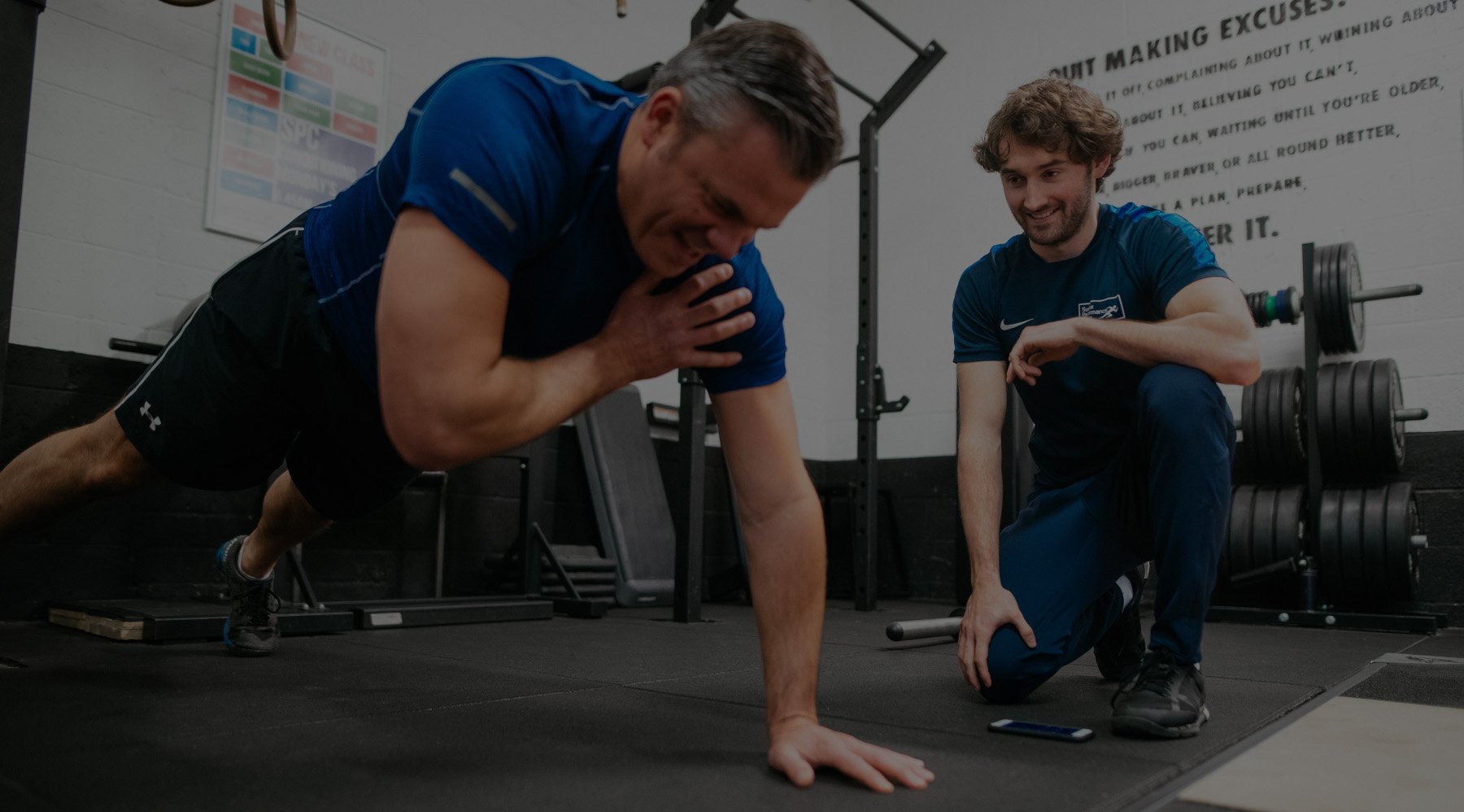 Matt kneeling beside a client, coaching a press-up